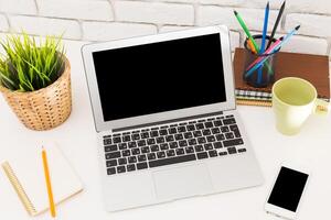 Workstation setup with laptop, stationery, and plants for a productive environment during the day photo