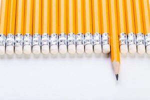 A collection of sharpened yellow pencils arranged neatly on a white surface during bright daylight photo