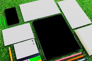 Desk setup on green grass with digital and stationary tools for creative work during daytime photo