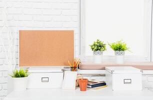 Minimalist workspace with corkboard, potted plants, and organized stationery during daylight hours photo