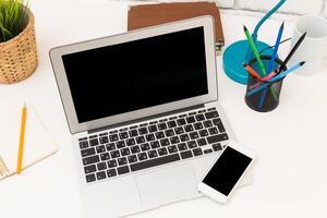 Modern workspace with laptop, smartphone, and office supplies on minimalist desk photo