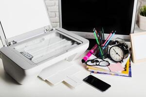 Office workspace with printer, clock, and colorful stationery on the desk photo