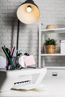 Desk setup with printer, stationery, and clock in a modern workspace highlighted by warm lamp light photo