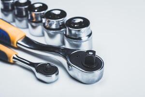 Set of shiny socket wrenches and ratcheting tools displayed on a light background photo