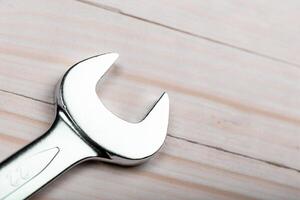 Close-up view of a shiny wrench resting on a wooden surface in a workshop setting during daylight hours photo