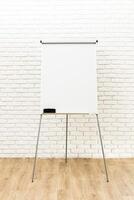 Flip chart set up against a white brick wall in a well-lit indoor space for a business meeting or presentation photo