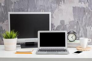 Minimalistic workspace with laptop, monitor, clock, and plants for a productive environment photo