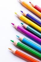 Vibrantly colored pencils lined up on a clean white surface ideal for creative artwork and drawing sessions photo