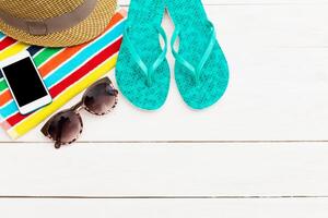 Bright summer essentials on a beach mat with flip flops, sunglasses, and a smartphone ready for relaxation photo