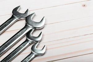 Various sizes of wrenches arranged on a wooden surface for toolbox organization in a workshop setting photo