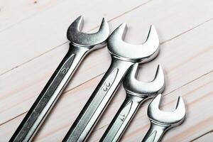 Set of four metal wrenches of varying sizes arranged neatly on a wooden surface during daytime photo