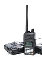 Multiple handheld radios stacked together with a prominent display unit resting on top in a bright setting photo