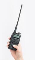 Handheld radio device held in a hand with a visible screen and antenna for communication in outdoor activities photo
