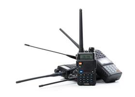 Multiple portable radios stacked together with extended antennas in a studio setting during daylight photo