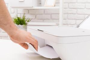 Printer usage in modern workspace with a hand retrieving printed document in a bright office setting photo