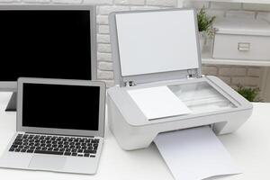 Printer and laptop setup on a modern desk in a cozy workspace during daylight hours photo