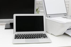 Workspace setup featuring a laptop and printer in a modern office environment photo