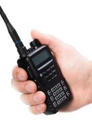 Handheld communication device held in a person's hand with a focused grip on the controls and antenna during a busy outdoor scenario photo
