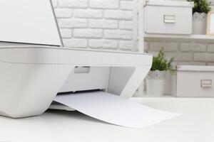 Modern printer in a bright office environment with paper being printed and greenery in the background photo