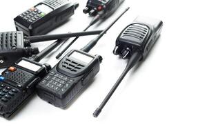 Communication devices arranged on a white surface with multiple two-way radios and antennas photo