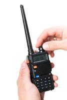 Hands adjusting the settings on a portable two-way radio in a bright indoor setting photo