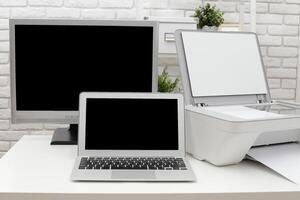 Modern workspace with a laptop, monitor, and printer in a bright, minimalistic setting photo