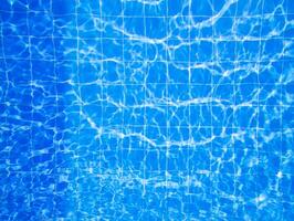 Clear blue water with sunlight reflections creating patterns in a swimming pool during a sunny day photo