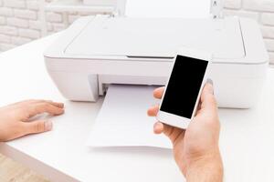 Using a smartphone to print documents from a printer in a modern workspace during bright daylight photo
