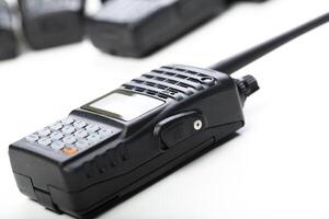 Modern two-way radio on a white surface with additional radios blurred in the background for communication use photo