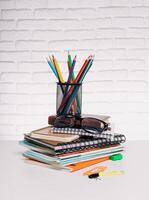 Colorful stationery arrangement on a table with notebooks and glasses in a bright environment photo