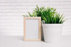 Decorative indoor plant with a wooden frame on a minimalist table against a white brick wall photo