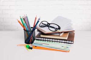 Colorful stationery items and glasses arranged on a desk with notepads ready for studying or creative work in a bright environment photo