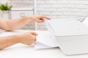 Manual paper handling at a home office setup includes printing tasks during the day photo