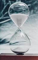 Elegant hourglass with fine white sand flowing, symbolizing the passage of time in a minimalist setting photo