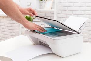 Person using a scanner to copy a document in a bright office environment during daytime photo
