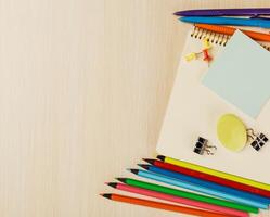 Colorful stationery arranged on a wooden table with notepad, paper clips, and markers in a bright workspace photo