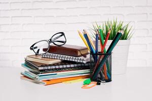 Desk setup with stationery supplies, notebooks, and glasses arranged in a neat workspace photo