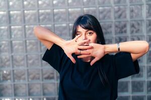 Woman performing expressive dance moves in a contemporary setting with textured glass background photo