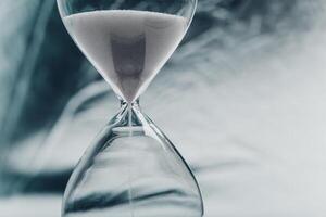 Elegant hourglass with fine sand flowing, symbolizing time passing in a minimalist setting photo
