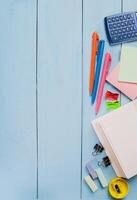 Colorful stationery on a blue table with a calculator, notepad, and various writing tools during a study session photo