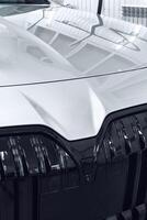 Close-up view of a modern car front showcasing sleek design and shiny chrome details in a well-lit indoor setting photo
