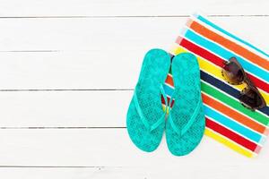 Colorful summer essentials including flip flops and sunglasses on a beach towel in a sunny setting photo