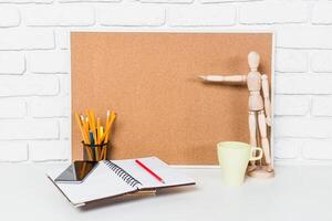 Creative workspace setup with stationery, a mannequin, and a corkboard for planning and inspiration photo