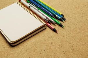 Notepad and colored writing instruments arranged on a textured surface for creative tasks photo