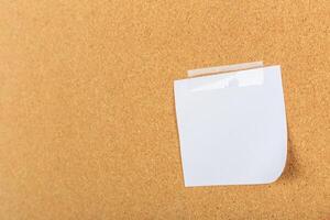 Blank sticky note adhered to corkboard in an office setting for reminders or notes photo