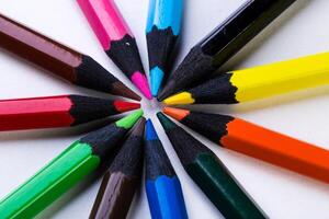 Vibrant colored pencils arranged in a circular pattern on a white surface at a creative workspace photo