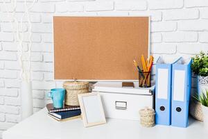 Stylish workspace with organized desk items, corkboard, and decorative elements in a modern setting photo