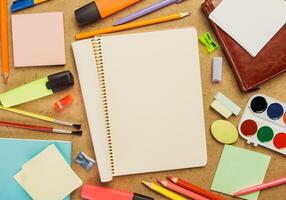 Creative workspace filled with various art supplies and a blank notebook on a rustic surface photo
