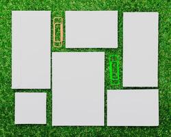Blank paper sheets and paper clips arranged on green grass in a creative setup during daytime photo