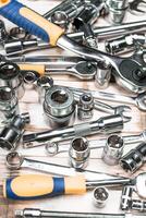 Collection of metallic tools scattered on wooden surface showcasing various sizes and types for mechanical and repair tasks photo